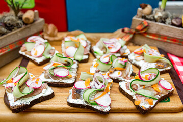 Sandwiches with salted herring, cucumber and radish on a wooden board.