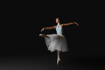 Young ballerina practicing dance moves on black background. Space for text