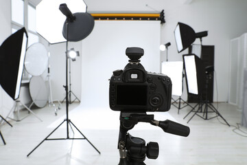 Tripod with camera and professional lighting equipment in modern photo studio