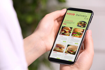Food delivery service. Woman choosing dish from menu on site using smartphone indoors, closeup