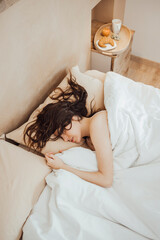 Young woman sleeping peacefully on cozy bed in morning