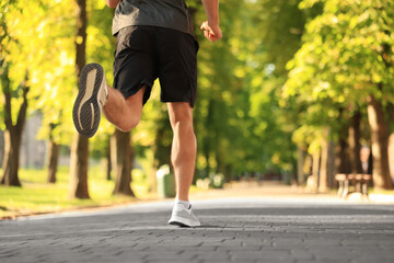Sporty man jogging in park on sunny day, closeup. Space for text