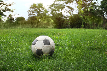 Dirty soccer ball on fresh green grass outdoors