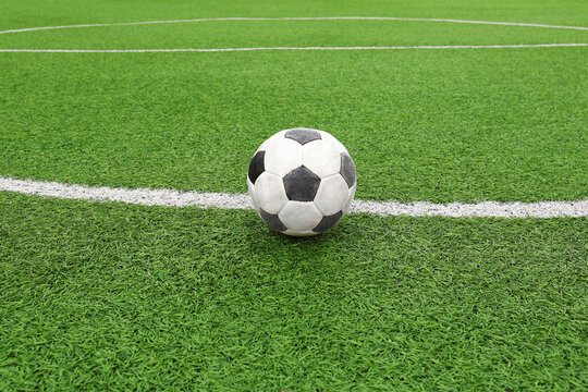 Dirty soccer ball on green football field