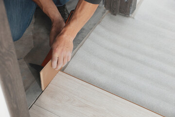 Worker installing new laminate flooring in room, closeup