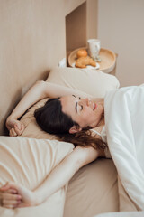 Obraz na płótnie Canvas Serene woman stretching arms after good sleep on bed
