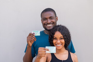 Two Nigerian citizens, male and female holding their voters card, PVC, smiling and happy