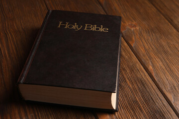 Hardcover holy Bible on wooden table, closeup
