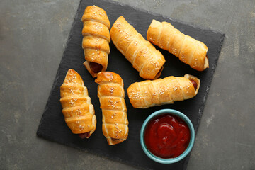 Delicious sausage rolls and ketchup on grey table, top view