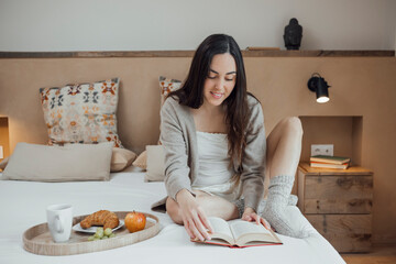 Obraz na płótnie Canvas Serene woman reading book on soft bed