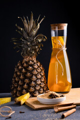 Pineapple Tepache. Fermented drink from pineapple served in bottle in low key. Dark background.