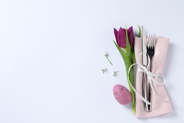 Cutlery set, Easter egg and tulip on white background, top view with space for text. Festive table...
