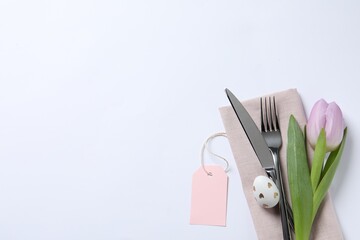 Cutlery set, Easter egg and tulip on white background, top view with space for text. Festive table...