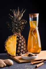 Pineapple Tepache. Fermented drink from pineapple served in bottle in low key. Dark background.