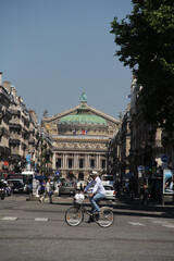 Obraz premium a cyclist through the streets of Paris with a view of the Opera Garnier in the background