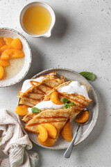Crepes with fresh mandarin, caramel, cream in the filling and mint leaves on white textured background. Maslenitsa or Pancake week traditional concept. Top view, text space, flat lay
