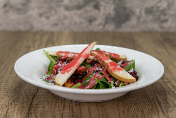 Tempting appetizer of a green salad, full of spinach, radicchio, fruit, and nuts served on a small plate