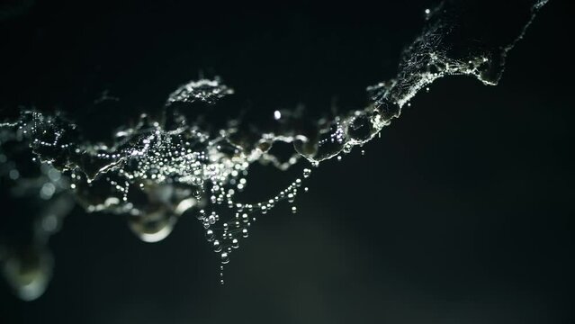 Dolly shot of drops dripping from rocks in cave