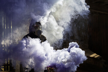 A man in gas mask holding a smoke bomb. Purple colorful smoke. Old czechoslovakian gas mask M-10(M). 