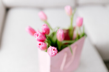Fototapeta na wymiar A close-up bouquet of pink tulips stands in a pink gift bag. Background for Valentine's Day. Gift for Mother's Day or Women's Day. spring background