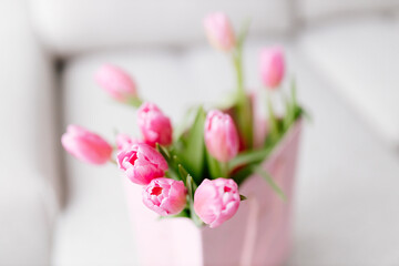 A close-up bouquet of pink tulips stands in a pink gift bag. Background for Valentine's Day. Gift for Mother's Day or Women's Day. spring background