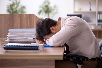 Young male employee and too much work in the office