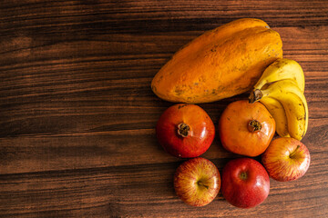 Many varieties of fruits laid out on a wooden table with copy space