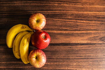 Top view of apples and bananas kept on a wooden table with copy apace
