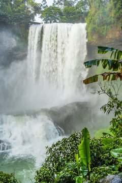 A gushing waterfall in a jungle setting with mist swirling at Dambri Falls In Vietnam