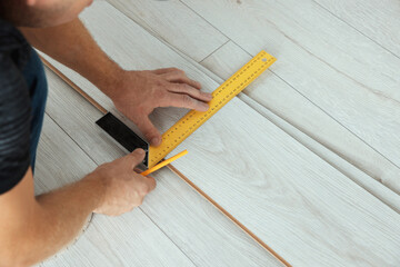 Fototapeta na wymiar Worker installing new laminate flooring in room, closeup