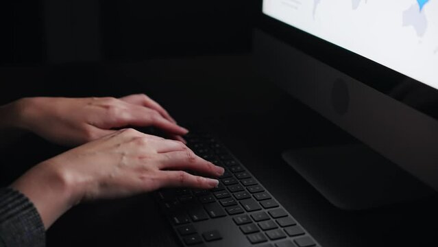 暗い部屋でタイピングする女性