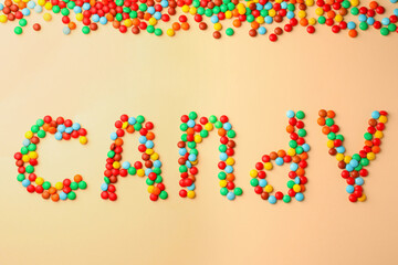 Word Candy made of tasty sweets on beige background, flat lay