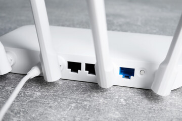 New white Wi-Fi router on grey textured table, closeup