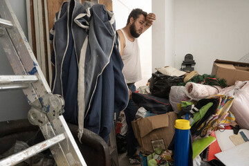 young adult man with hoarding disorder standing in a dirty room - obrazy, fototapety, plakaty