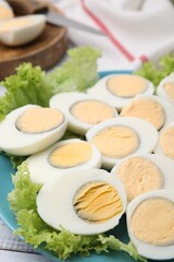 Fresh hard boiled eggs and lettuce on white wooden table