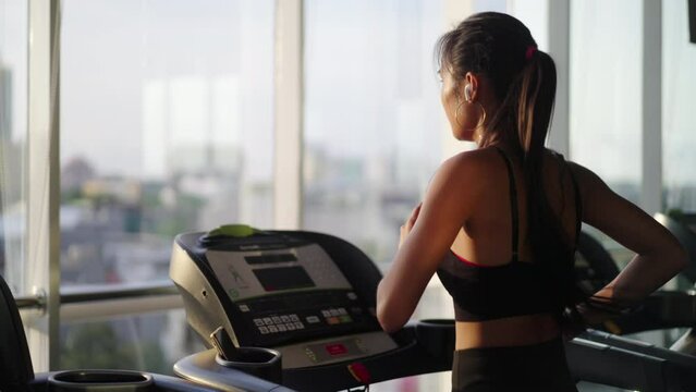 An attractive young asian woman running on treadmill with beautiful cityscape. Woman running for health