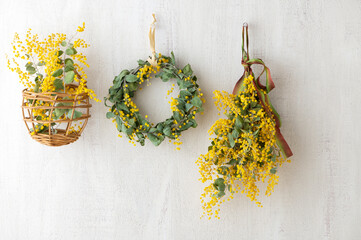 白い壁に飾られたミモザのリース　ミモザのスワッグ