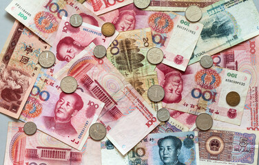 Yuan coins on heap of yuan paper money. Chinese economy and finance. Currency background. Trade relations of countries,.inflation, investment, business and lending. Flat lay, closeup