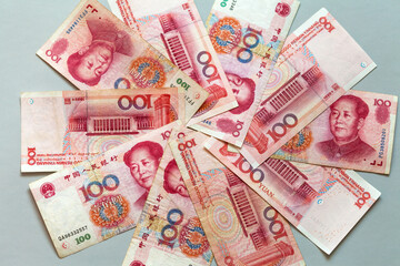Paper money in denominations of 100 yuan are laid out in a circle on a light table. Chinese economy...