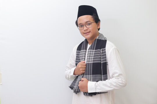 Portrait of young Asian muslim man standing with cool pose and holding his sarong. Isolated image on white background