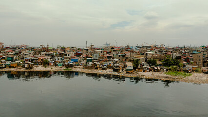 Fototapeta na wymiar Slums in Manila near port on the bank of a river polluted with garbage, aerial view.