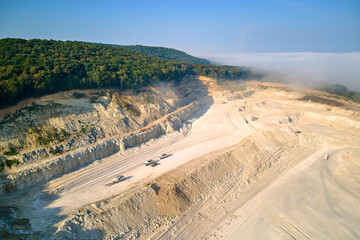 Aerial view of open pit mining of limestone materials for construction industry with excavators and dump trucks