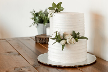 Pastel de novia blanco con decoración en mesa de madera y flores