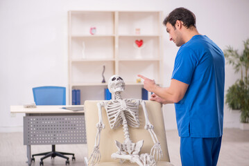 Obraz premium Young male doctor and skeleton patient in the clinic