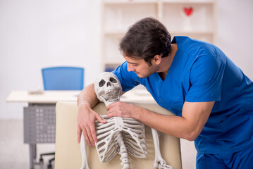 Young male doctor and skeleton patient in the clinic