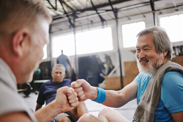Fitness, gym and men with fist bump for senior support, personal trainer goals and exercise progress. Japanese or asian elderly person with teamwork, achievement and success hand sign for training