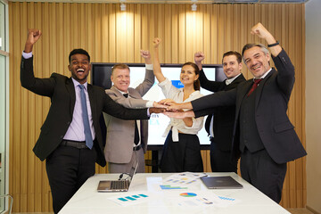 businesspeople raise arms up and celebrating success at work in a conference room