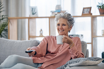 Senior woman, sofa and coffee to relax with remote for television, video or movies with smile in...