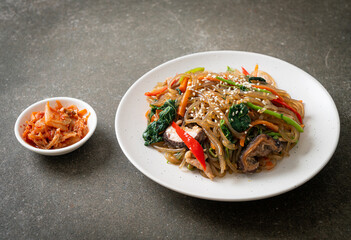 japchae or stir-fried Korean vermicelli noodles with vegetables and pork topped with white sesame