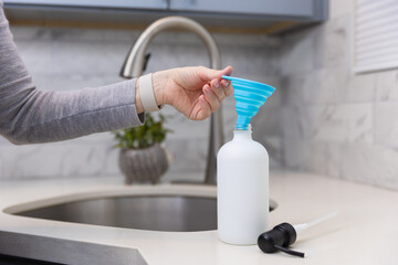 Woman refilling the soap dispencer with a funnel
